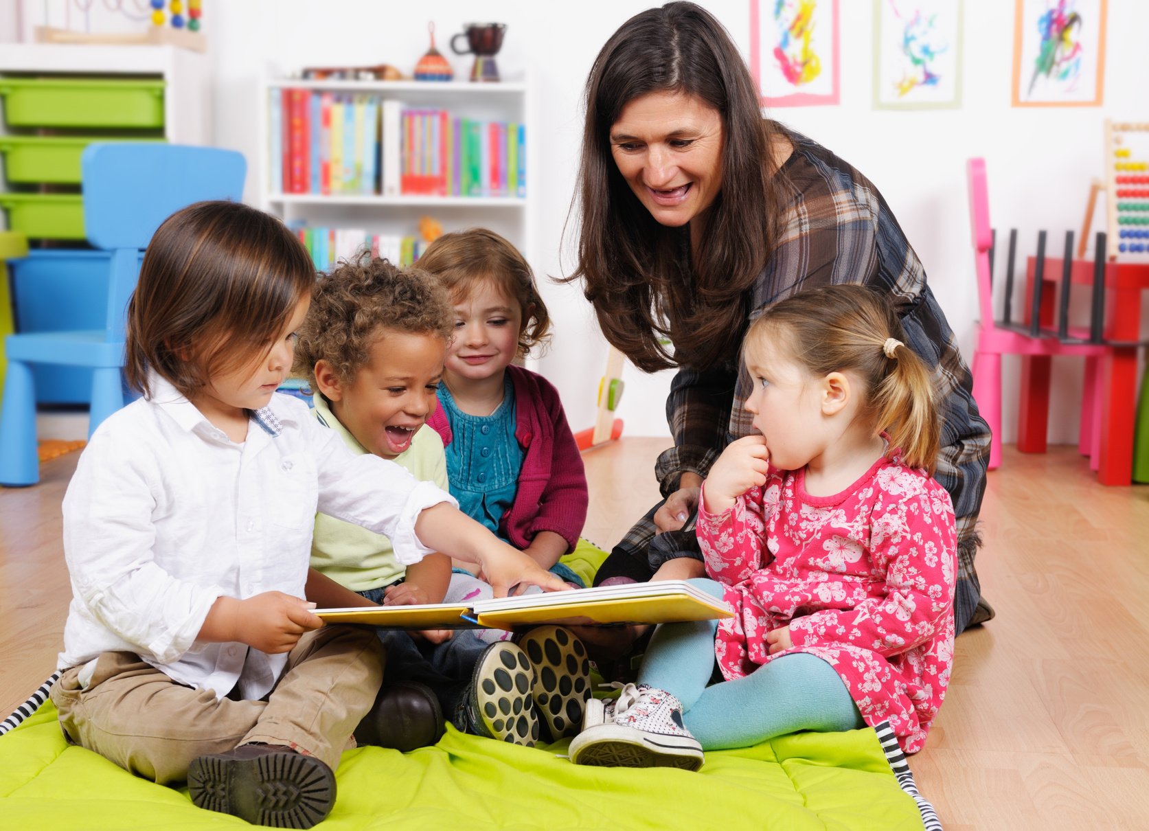 Group Of Little Children Enjoying Storytime In A Nursery Setting